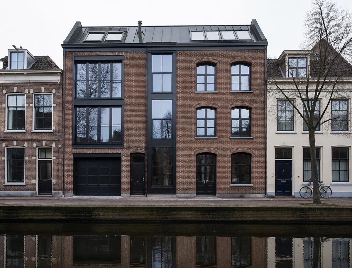 Urban brick residence with dark metal windows reflected in a canal